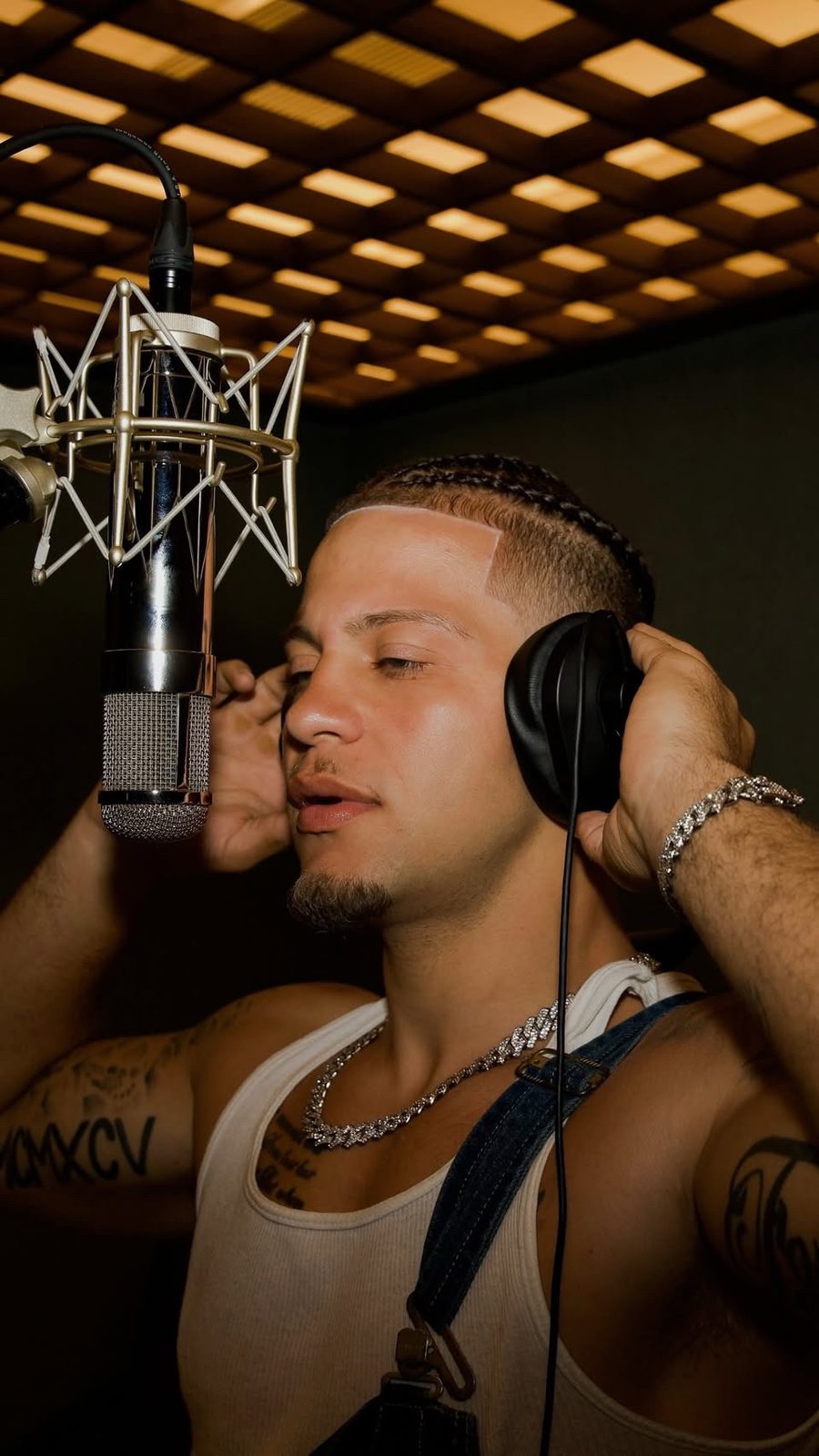 Artistic studio portrait of Rome Rizzo at a recording microphone wearing headphones