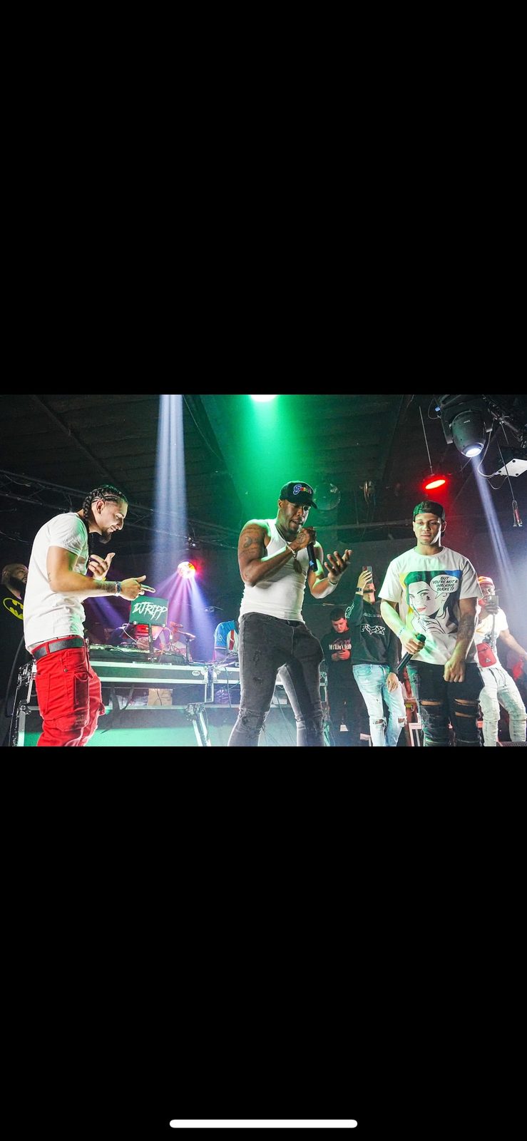 Rome Rizzo on stage with other performers under green stage lights