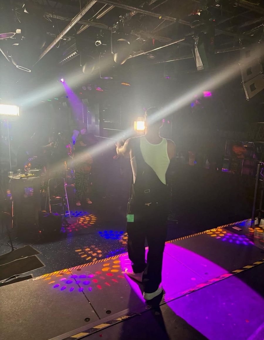 Rome Rizzo standing under stage lights during a live performance